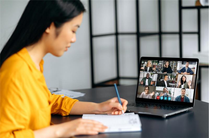 a woman on a virtual meeting, taking notes
